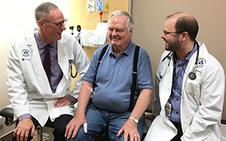 Patient Harold Black smiles as he sits between Dr. Philip Wells (left) and Dr. Marc Carrier (right).